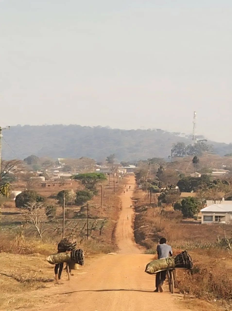 A long unpaved road leading through a rural community